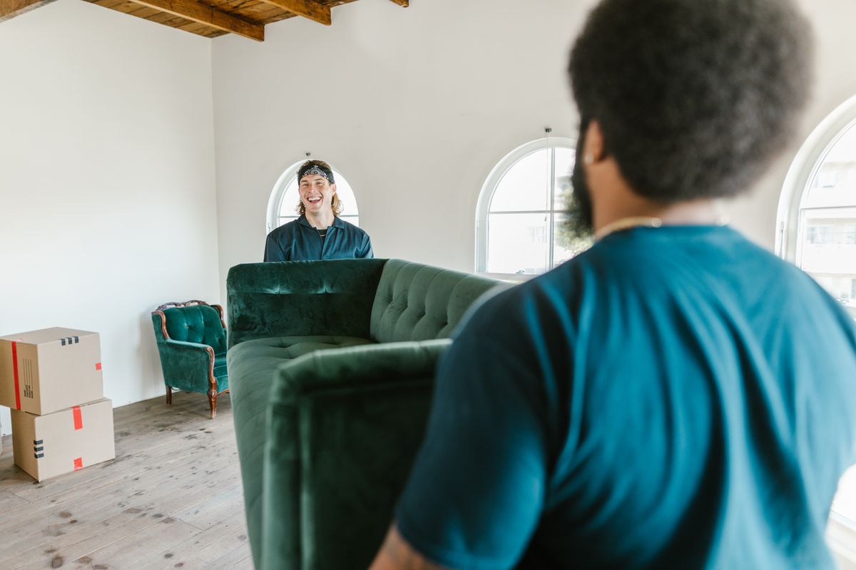Movers carrying a sofa through a bright city apartment